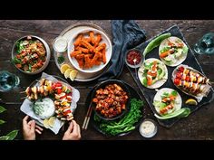 a table topped with plates of food next to bowls of salads and dipping sauce