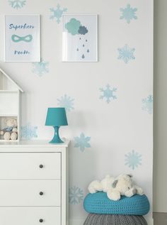 a white dresser sitting next to a wall with snowflakes on it and a blue lamp