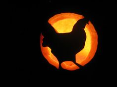 a black and orange pumpkin with a chicken in it's center surrounded by dark background