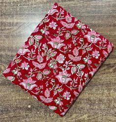 a red and pink floral print pocket square on a wooden table with wood grain flooring