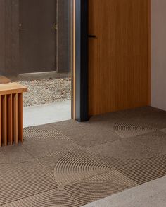 a wooden bench sitting on top of a floor next to an open door in front of a building