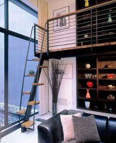 a living room filled with furniture next to a tall book shelf covered in vases