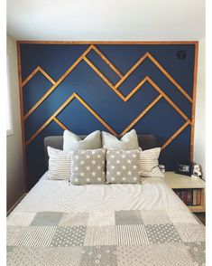 a bed with white and gray pillows on it in front of a blue headboard