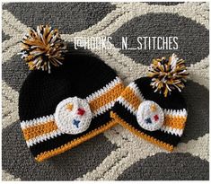 a black and yellow knitted hat with two pom poms sitting on top of it