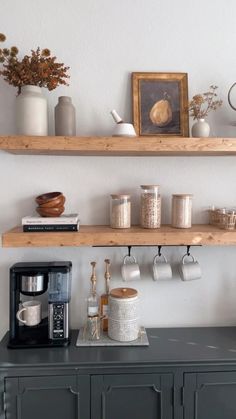 two open shelves above a coffee maker and some cups on top of a black cabinet