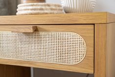 a close up of a drawer with some plates on it and a vase in the background