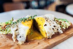 a wooden cutting board topped with food on top of a table