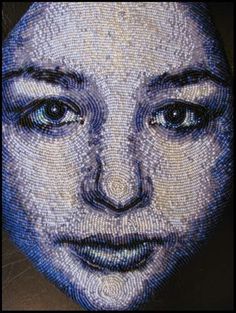 a woman's face is made out of mosaic tiles and has dark blue eyes