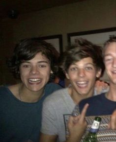 two men and one woman are posing for the camera with beer bottles in their hands