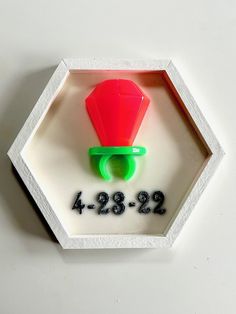 a red and green object is in a white hexagonal box with numbers on it