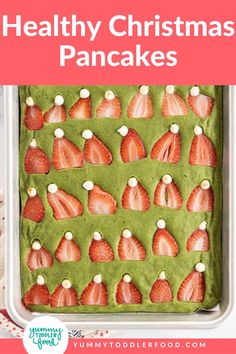 a pan filled with green pudding covered in strawberries and topped with marshmallows