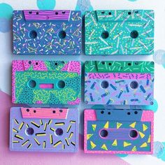 four different colored cassettes are arranged on a pink and blue background with confetti sprinkles