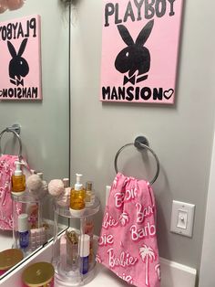 a bathroom sink with personal care items on it and a pink towel hanging from the wall