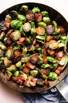 brussel sprouts and bacon in a skillet with a spoon on the side