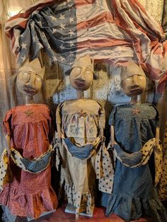 three wooden mannequins are standing in front of an american flag and some fabric