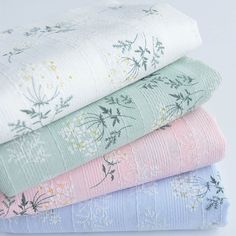 four folded sheets stacked on top of each other in different colors and patterns, all with floral designs