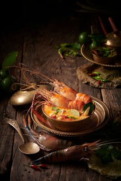 some food is in a bowl on a table with spoons and utensils