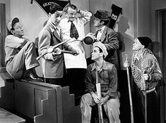 a group of men standing around each other in front of a tv with hats on