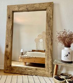 a mirror sitting on top of a wooden table next to a vase and potted plant