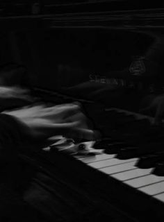 blurry photograph of piano keys in black and white photo with person sitting at the keyboard