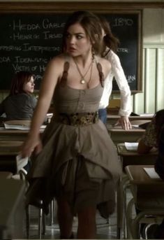 a woman standing in front of a chalkboard with her hand on the back of her head