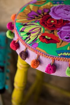 a colorful stool with tassels and flowers on it