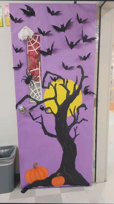 a door decorated with bats and a tree on it, next to a trash can