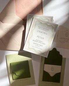 the wedding stationery is laid out on top of each other, including envelopes and cards