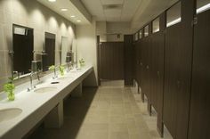 a long row of sinks in a bathroom with mirrors and lights on the wall above them