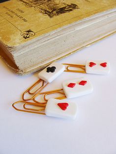 four pins with hearts on them sitting next to an old book