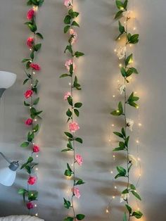 some pink and white flowers are hanging on the wall next to a bed with lights