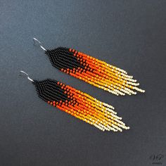 two pairs of beaded earrings with orange and white beads on them, sitting on a gray surface