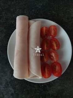 a white plate topped with meat and tomatoes on top of a black counter next to a knife