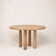 a round wooden table sitting on top of a white floor