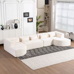 a large white couch sitting on top of a wooden floor next to a window in a living room