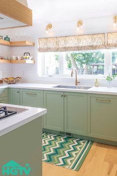 a kitchen with green cabinets and white counter tops, an area rug on the floor