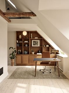 an attic office with wooden shelves and desk in the center, along with bookshelves