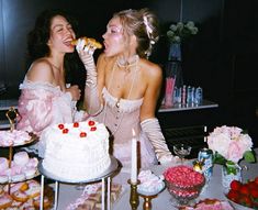 two women sitting at a table eating cake