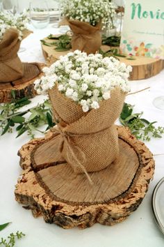 the table is set with flowers in burlocked vases on wood slices