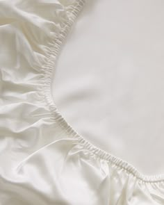 an unmade bed with white sheets and pillows