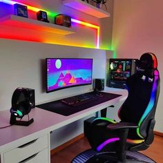 a desk with a computer and gaming chair in front of it, all lit up by colorful lights