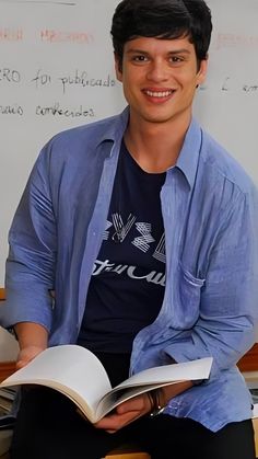 a young man sitting down reading a book