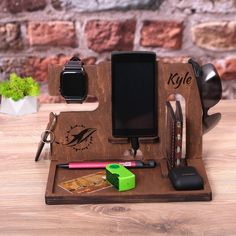 an apple watch, cell phone and other personal items are on a wooden stand next to a brick wall