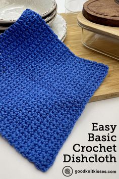 a blue crochet dishcloth sitting on top of a wooden cutting board next to plates