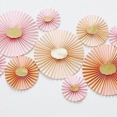 pink and gold paper fans arranged on a white surface