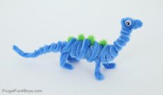 a blue toy with green hair on it's tail and eyes, sitting in front of a white background