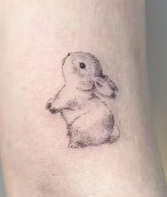 a black and white photo of a small rabbit tattoo on the right side of the leg