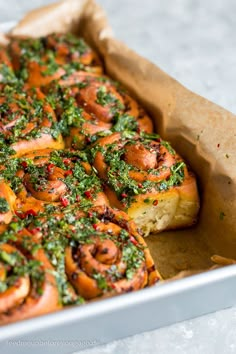 a casserole dish filled with shrimp and pesto covered bread in a baking pan