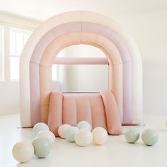 some balloons are laying on the floor in front of a pink arch and white walls