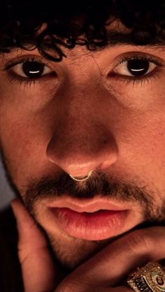 a close up of a person with a ring on his finger and wearing a hat